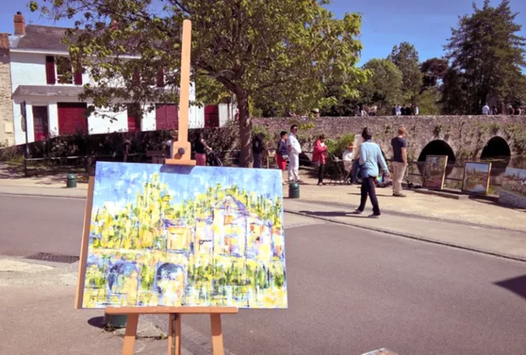 Un tableau exposé sur un chevalet dans la rue pendant le festival d'artistes de Rocheservière et du public est en train de se déplacer sur le vieux pont
